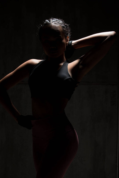 Asian Tan Skin Fitness femme exercice étirement bras boxe poids punch en arrière-plan sombre, studio éclairage gradient gris haut ombre lumière faible exposition copie espace, concept Femme peut faire du sport 6 paquets
 - Photo, image