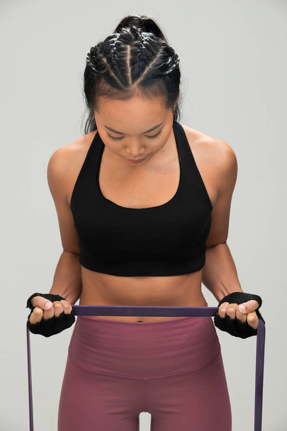 Asian Tan Skin Fitness woman exercise warm up stretch resistance bands wear Black sport bra mulberry pants, studio lighting gray background copy space, concept - Φωτογραφία, εικόνα