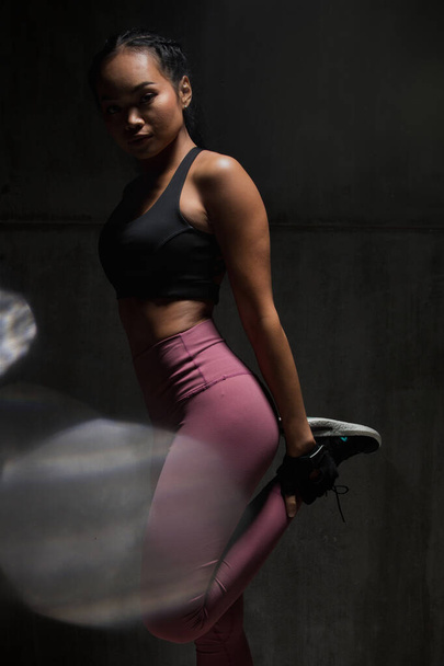 Asian Tan Skin Fitness woman exercise stretch arms boxing weight punch in Dark background, studio lighting gradient gray top light shadow low exposure copy space, concept Woman Can Do Sport 6 packs - Photo, image