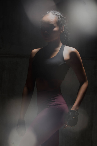 Asian Tan Skin Fitness vrouw oefening stretch armen boksen gewicht punch in donkere achtergrond, studio verlichting gradiënt grijs top licht schaduw lage blootstelling kopieerruimte, concept Woman Can Do Sport 6 packs - Foto, afbeelding