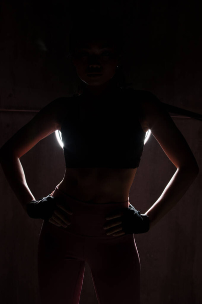 Asyalı bronz tenli spor kadın kollarını esneterek boks yapıyor. Arka planda, stüdyo aydınlatma gradyanı gri üst gölge düşük pozlama fotokopi alanı, konsept kadın 6 paket spor yapabilir. - Fotoğraf, Görsel