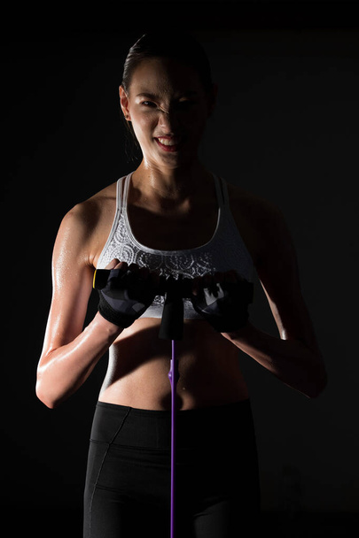 Azjatycki szczupły Fitness kobieta ćwiczenia rozciąganie nogi ramiona pas oporu we mgle dym ciemne tło niskie środowisko ekspozycji, studio oświetlenie przestrzeń kopia, koncepcja kobieta może zrobić Sport 6 paczek - Zdjęcie, obraz