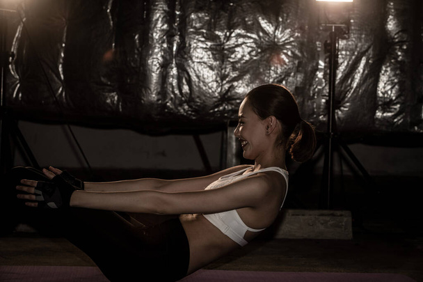 Asiático delgado fitness mujer ejercicio estiramiento piernas brazos sentarse en niebla humo oscuro fondo bajo exposición ambiente, estudio iluminación copia espacio, concepto mujer puede hacer deporte 6 paquetes
 - Foto, Imagen