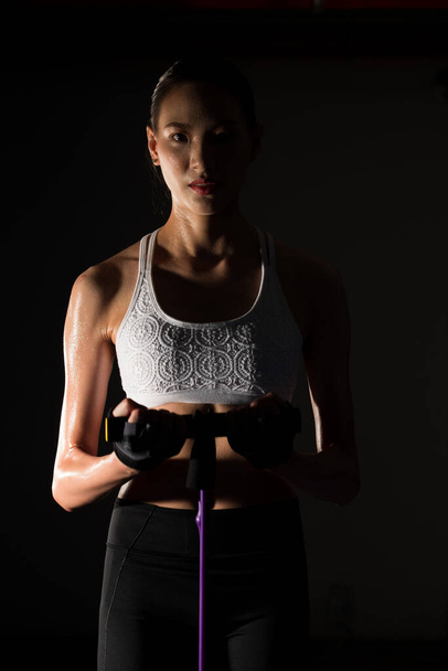Asian slim Fitness woman exercise stretching legs arms resistance band in Fog Smoke Dark background low exposure environment, studio lighting copy space, concept Woman Can Do Sport 6 packs - Photo, Image