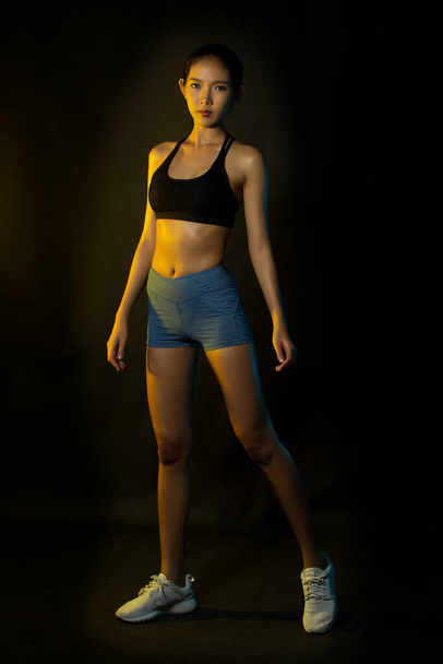 Ázsiai Tan Skin Fitness Lány gyakorlat viselni kék fekete rövid boksz melltartó köd füst Sötét háttér környezet, stúdió világítás másolás tér b & w monoton szín, koncepció Woman Can Do Sport - Fotó, kép