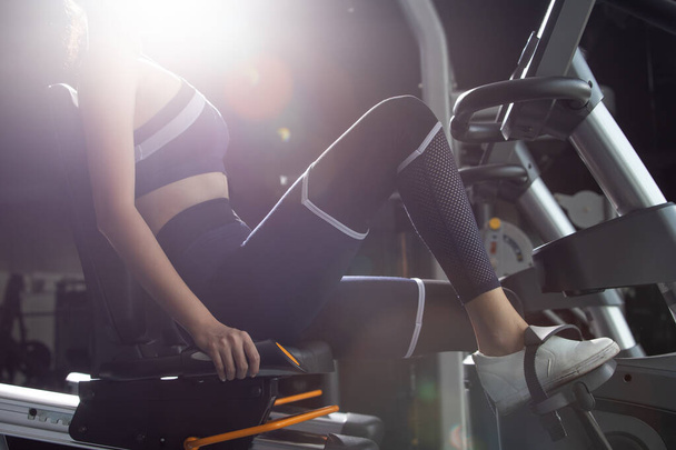 Asian slim Fitness woman black hair sport bra exercise warm up on pushing machine cycling bicycle bike in Gym. Concept female Can Do athlete Sport healthy, no face back light - 写真・画像