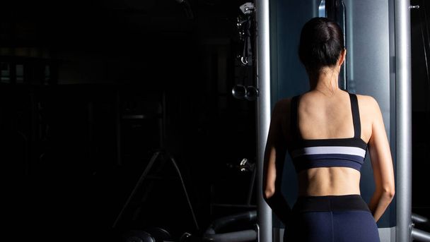 Back side view Asian slim Fitness woman black hair sport bra exercise warm up on Pull down machine Weight Muscle Hands Arms in Fit Gym. Concept female Can Do athlete Sport healthy, copy space - 写真・画像
