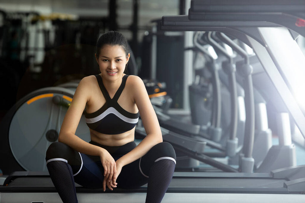 Asian slim Fitness woman black hair sport bra white shoe exercise warm up and sit tired on Treadmill in Fit Gym. Concept female Can Do athlete Sport healthy, copy space - 写真・画像