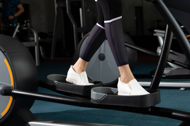 Beenwitte schoenen van slanke Fitness vrouw trainen opwarmen op push klimmachine elliptisch kruis in Fit Gym. Concept vrouw kan doen atleet Sport gezond, kopiëren ruimte - Foto, afbeelding