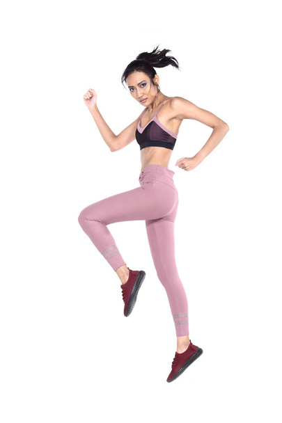 Asiática hermosa chica de fitness en sexy lindo negro sujetador deportivo púrpura pantalones de spandex Ejercicio de calentamiento en la sala de estudio blanco, salto de longitud completa
 - Foto, Imagen