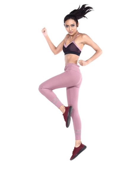 Asiática hermosa chica de fitness en sexy lindo negro sujetador deportivo púrpura pantalones de spandex Ejercicio de calentamiento en la sala de estudio blanco, salto de longitud completa
 - Foto, Imagen