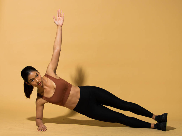 Asian slim Fitness woman exercise warm up stretch arms legs, planking, studio lighting yellow beige mustard background shadow copy space, concept Woman Can Do athlete Sport 6 packs - Photo, Image