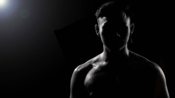 Ασιατική Big Muscle Fitness Man άσκηση δείχνουν τα χέρια, δικέφαλος, στήθος με ιδρώτα από τη θερμότητα. Νεαρός Αθλητισμός Αρσενικό έξι πακέτα πυροβολούν σε χαμηλή έκθεση φωτισμού κλειδί με σκιώδη αντίθεση, αντιγραφή χώρου - Φωτογραφία, εικόνα