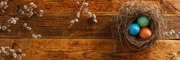 Still life of easter eggs in a bird's nest on a wooden background. Rustic. Easter celebration concept. Copy space. Flat lay - Photo, Image