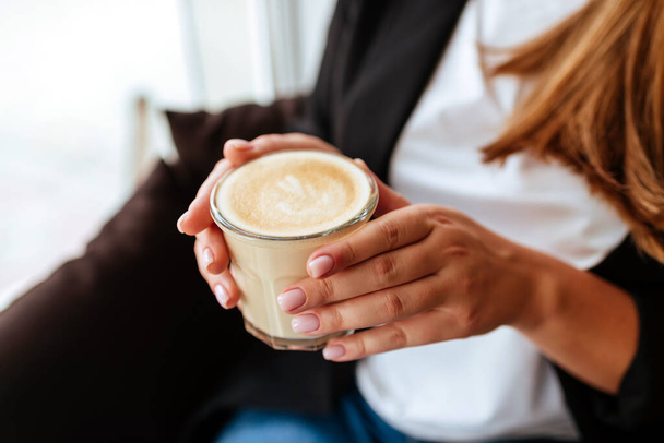 hands holding cup of coffee in coffee shop - Fotó, kép