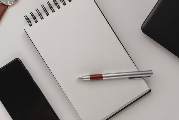 Minimalistische gedetailleerde werkruimte achtergrond, een open spiraal notebook met een blanco blad, een pen en een mobiele telefoon. Kopieer ruimte bovenaanzicht, platte lay, mockup. - Foto, afbeelding