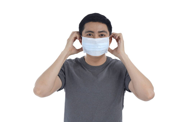 Asian young man in flu mask against with a corona virus pandemic, or prevent flu disease or cold during winter - 写真・画像