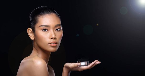日焼けした肌若いファッションアジアの女性モデル現在、製品の治療パッケージのコピースペースを示す手掌、ターンサイドリアビュー肩トップレス、スタジオ照明黒背景広告領域 - 写真・画像