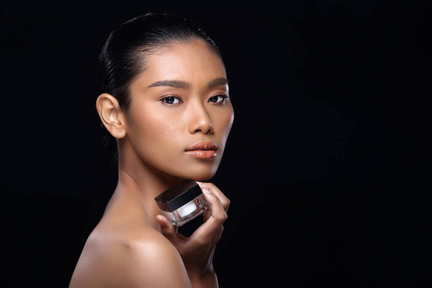 garbowana skóra młody moda azjatycki kobieta model obecny pokazując produkty leczenie pakiet przestrzeń na dłoni dłoni, skręcić w bok widok z tyłu ramię topless, studio oświetlenie czarny tło reklama obszar - Zdjęcie, obraz
