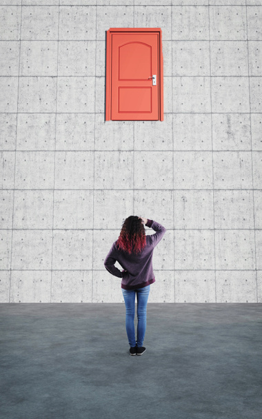 Μπερδεμένη γυναίκα κοιτάζει μια κλειστή πόρτα στον τοίχο.. - Φωτογραφία, εικόνα