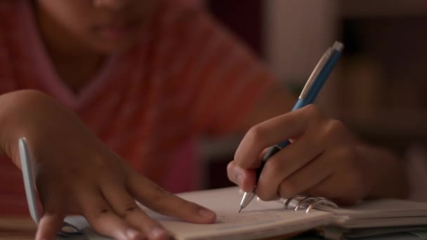 Close up hand of a little girl writing on notebook. Female schoolchild making notes on a diary. Doing homework with writing material. Education concept. - Footage, Video
