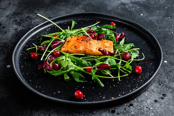 Seafood salad with trout, arugula, lettuce and cranberries. Black background. Top view. - Photo, Image