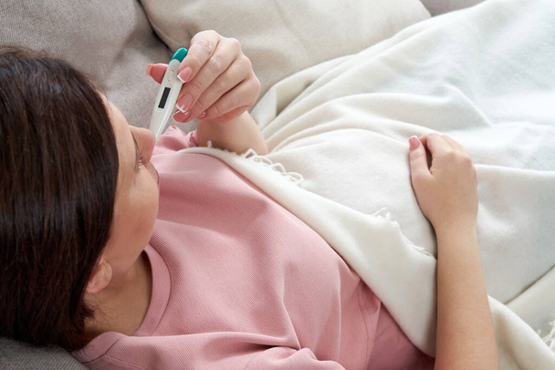 Mujer sosteniendo un termómetro digital. Concepto de fiebre, gripe, virus y cuarentena
  - Foto, Imagen