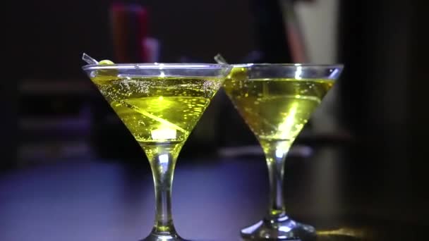 Een close-up. glazen met martini of gin op de bar. Martini met olijf. - Video