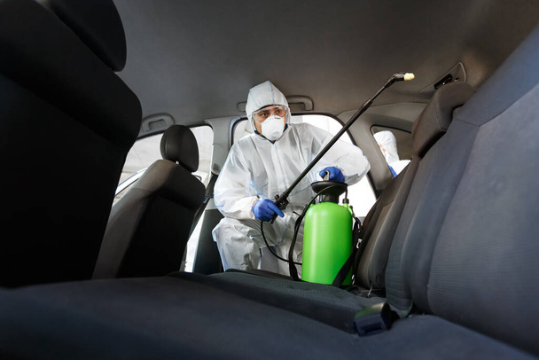 Hot steam disinfection of car seats in coronavirus hazmat - Foto, afbeelding