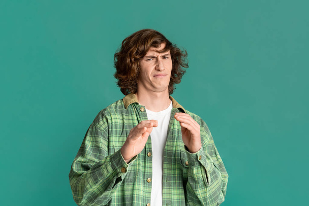 Expressing disgust. Millennial guy with curly hair feeling repulsed on color background - Photo, Image