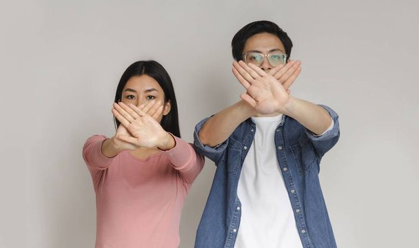 Joven asiático pareja holding cruzado palmas contra bocas
 - Foto, Imagen