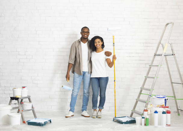 Couple with repair tools and paint on white brick wall background - Foto, imagen