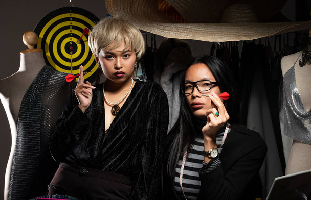Duo Tomboy blonde hair, Ladyboy black long Fashion Designers hold Darts in hand and look at camera. LBGT Transgender tailor styling new online store shop social media. Dartboard target objective goal - Photo, Image