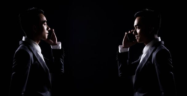 Групповой пакет Коллаж портрета 20-х Азиатский бизнесмен под студийным освещением низкой экспозиции подсветки силуэт темный фон, мужчина в правильном сером костюме говорить друг через смартфон в тени, скопировать пространство
 - Фото, изображение