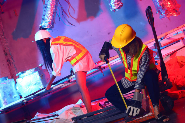 Twee mooie Aziatische Architect Engineer vrouw in geel harde hoed, veiligheid groot, mega telefoon, concept vrouw kan doen vernietiging bouwplaats gebied kamer Hand pallet truck mode rood blauwe achtergronden - Foto, afbeelding