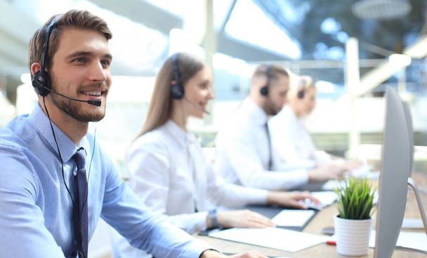 Portrait of call center worker accompanied by his team. Smiling customer support operator at work - Φωτογραφία, εικόνα
