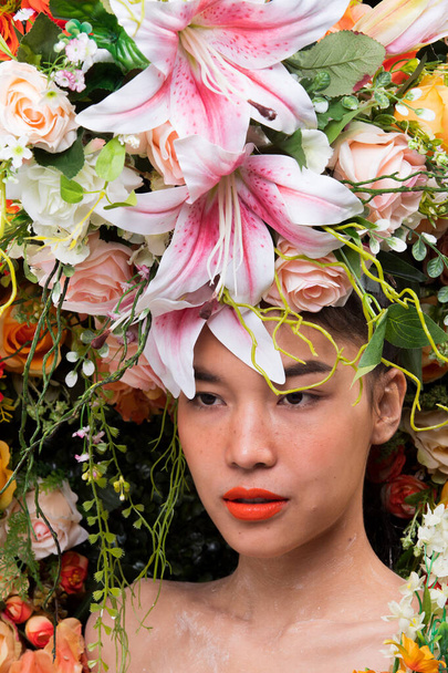 Gül kırmızısı arkaplanda çiçek çelengi... Güzel Asyalı Kadın portresi için güzel bir bahar yazı... Parfüm, Kozmetik, Ruj konsepti reklamları için stüdyo aydınlatma kampanyası... - Fotoğraf, Görsel