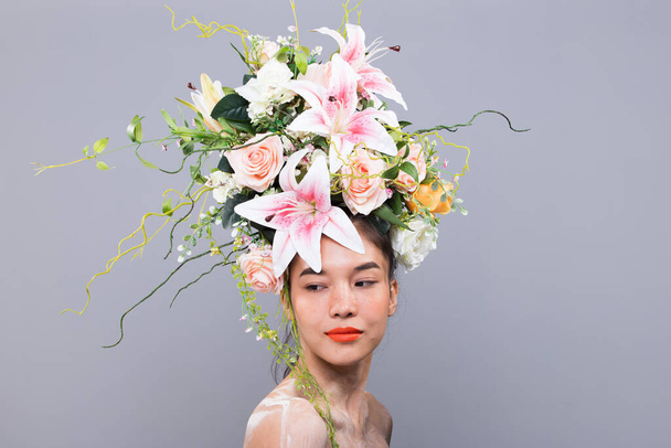 Kroon van verse bloem als koningin op Aziatische zeer mooie vrouw Fashion Posing express voor reclame campagne lippenstift, cosmetische, parfum. Studio verlichting geïsoleerde grijze achtergrond kopieerruimte - Foto, afbeelding