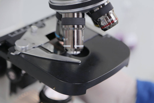 Giovane maschio scienziato guardando attraverso un microscopio in un laboratorio facendo ricerca, analisi microbiologica, medicina. - Foto, immagini