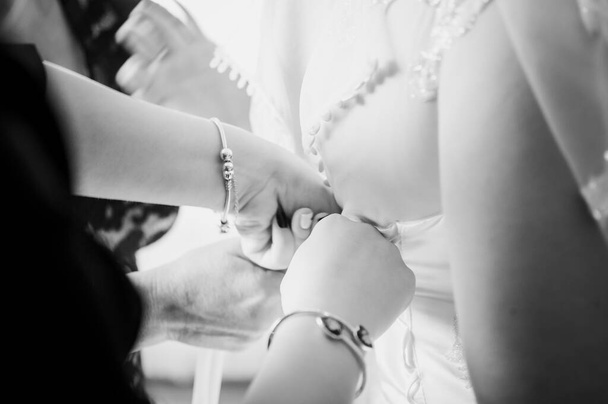 Las damas de honor ayudan a la novia a usar vestido de novia en blanco y negro
 - Foto, imagen