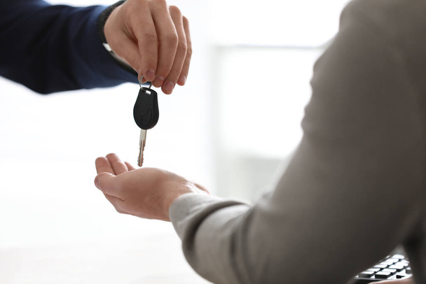 Salesman giving key to customer on light background, closeup. Buying new car - 写真・画像