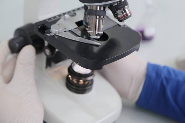 Hombre joven científico mirando a través de un microscopio en un laboratorio haciendo investigación, análisis microbiológico, medicina
. - Foto, imagen