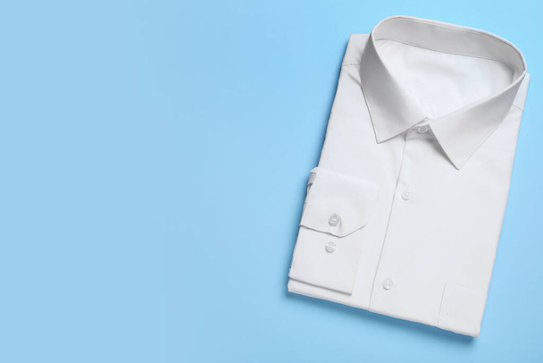 Стильная белая рубашка на светло-синем фоне, вид сверху с пространством для текста. Услуги химчистки
 - Фото, изображение