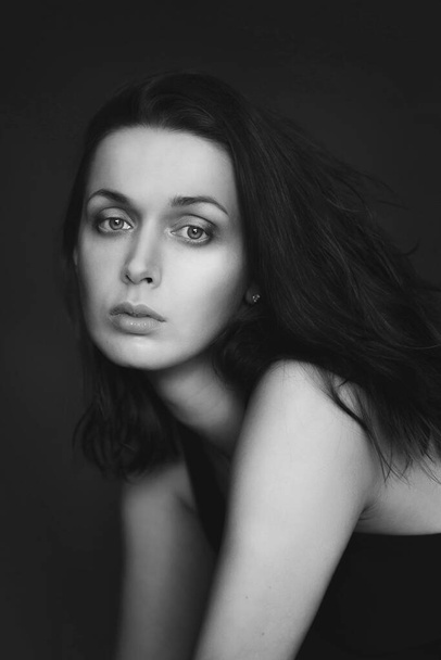 Портрет женщины в черно-белом, она смотрит прямо в камеру с широко открытыми глазами
 - Фото, изображение