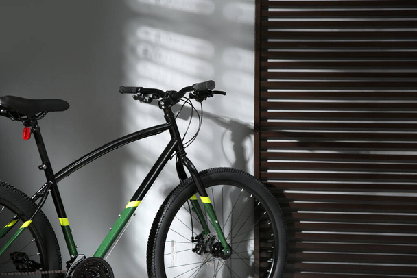 Modern black bicycle near grey wall indoors - 写真・画像