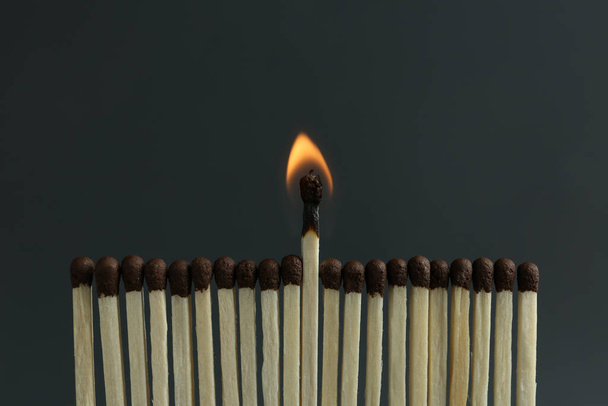 Burning match among unlit ones on black background, closeup - Zdjęcie, obraz