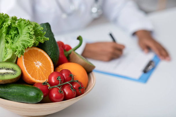 Kulho tuoreita hedelmiä ja vihanneksia ravitsemuslääkärillä työpaikalla
 - Valokuva, kuva
