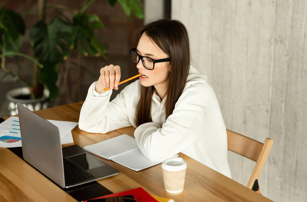 Девушка в очках анализирует работу, держит карандаш
 - Фото, изображение