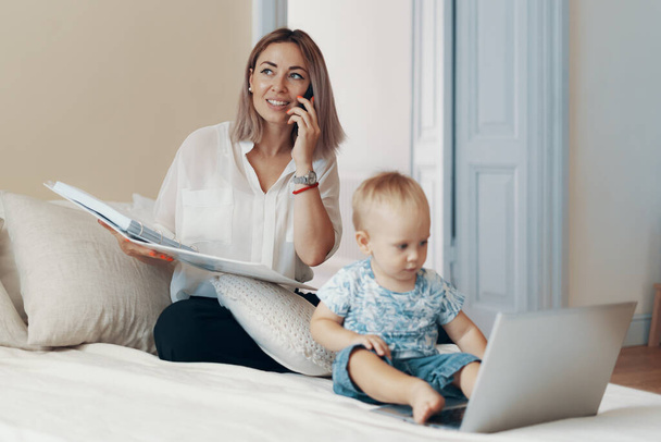 Business mom talking on a cell phone. Multi-tasking, freelance and motherhood concept - 写真・画像