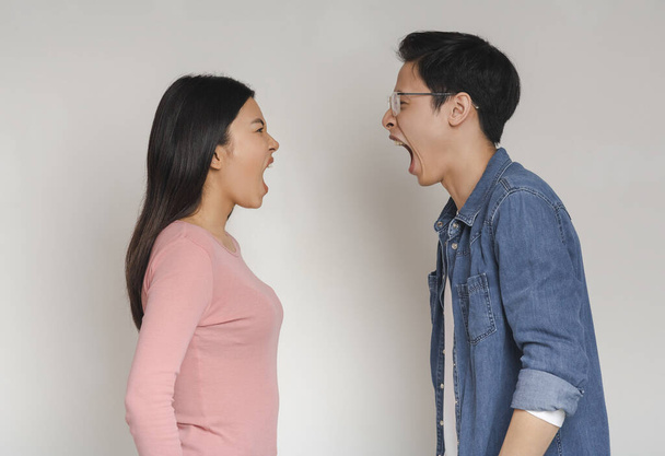 Asian man and woman shouting over grey background - Фото, изображение